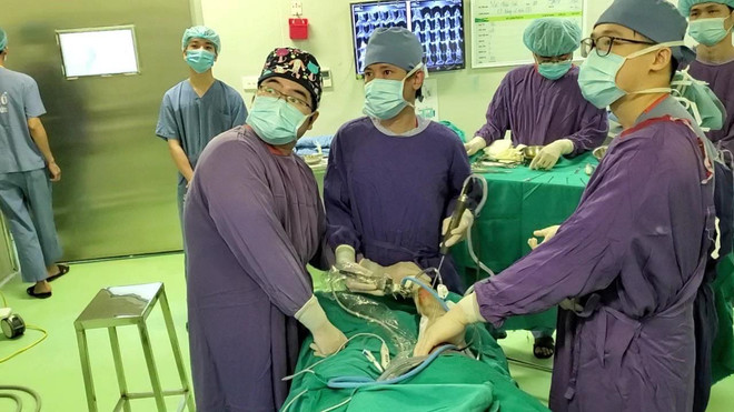 Phó Giáo sư-Tiến sỹ Nguyễn Mạnh Khánh cùng ê kíp thực hiện ca phẫu thuật. (Nguồn: PV/Vietnam+) Lần đầu thực hiện thành công phẫu thuật nội soi ghép sụn khớp nhân tạo ảnh 1