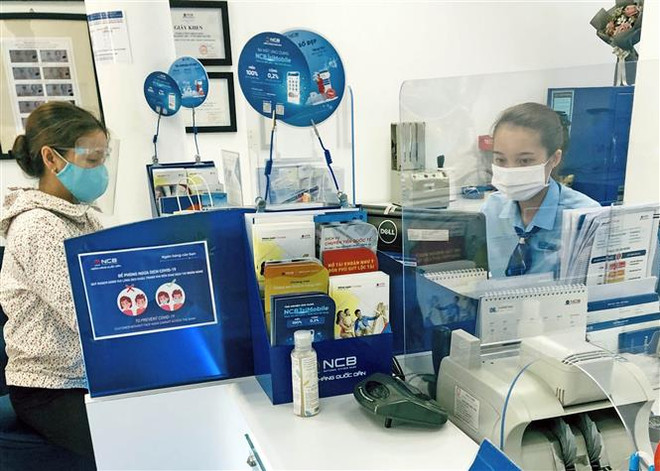 Khách hàng giao dịch tại Ngân hàng TMCP Quốc Dân. (Ảnh: Trần Việt/TTXVN) Thị trường tiền tệ trong nước sau quyết định tăng lãi suất của Fed ảnh 1