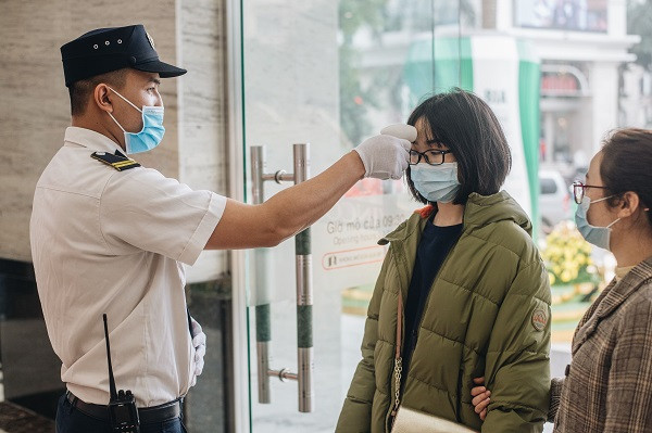 Bảo vệ tiến hành đo thân nhiệt cho khách ghé thăm trung tâm thương mại. (Nguồn: Vietnam+) COVID-19: Người dân bình tĩnh quay trở lại nhịp sống bình thường ảnh 7