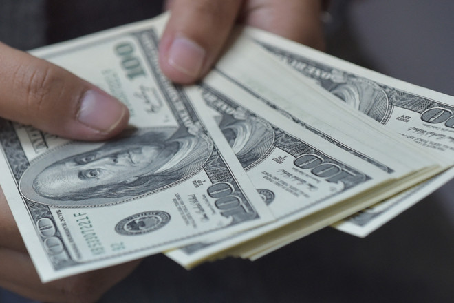 Đồng tiền mệnh giá 100 đô la Mỹ. (Ảnh: AFP/TTXVN) Đồng USD tăng, áp lực tỷ giá có đáng lo ngại ở những tháng cuối năm? ảnh 1