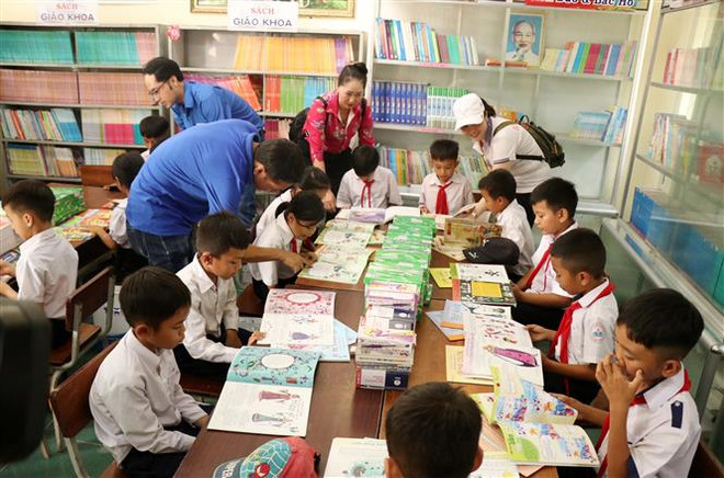 Học sinh trường tiểu học Nơ Trang Lơng đọc sách từ chương trình Tủ sách Đinh Hữu Dư trao tặng. (Ảnh: Hoài Thu/TTXVN) Tủ sách Đinh Hữu Dư đến với học sinh vùng khó khăn của Đắk Lắk ảnh 1
