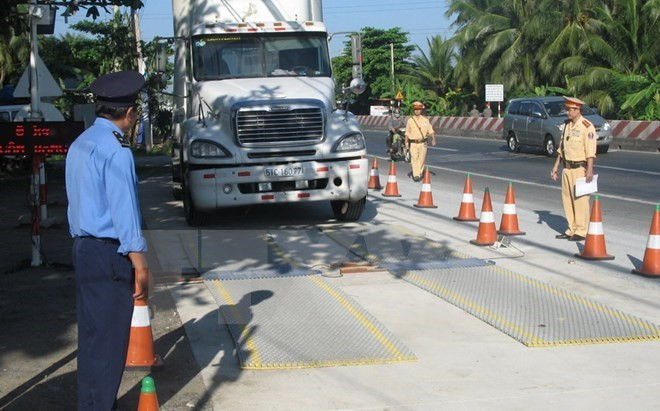 Lực lượng chức năng tiến hành kiểm soát tải trọng xe. (Ảnh: TTXVN) Xe quá tải "nhờn thuốc", doanh nghiệp đứng bên bờ vực phá sản ảnh 1