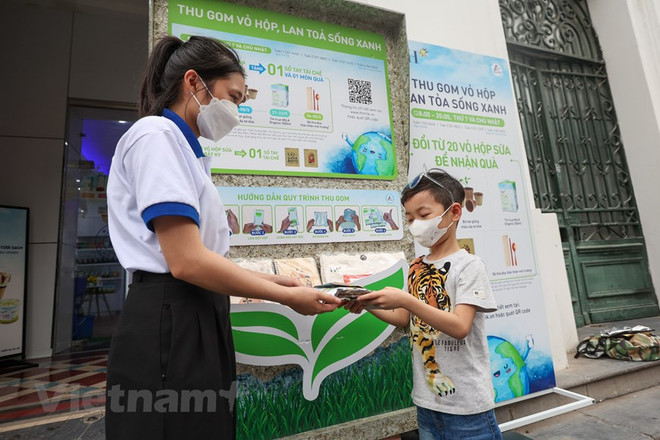 Bé Trần Ngọc Lục Bảo, 8 tuổi, háo hức mang vỏ hộp sữa đến đổi quà tặng là cuốn sổ tái chế. (Ảnh: Minh Sơn/Vietnam+) Thu gom, tái chế vỏ hộp sữa: Việc tử tế… ‘gieo mầm’ lối sống xanh ảnh 1