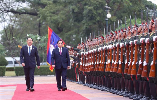Thủ tướng Phạm Minh Chính và Thủ tướng Lào Sonexay Siphandone duyệt đội danh dự. (Ảnh: Dương Giang/TTXVN) Báo Lào đưa tin chào mừng chuyến thăm của Thủ tướng Phạm Minh Chính ảnh 1