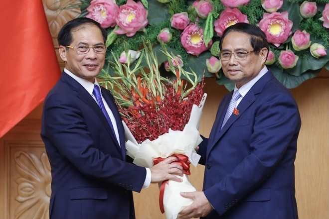 Thủ tướng Phạm Minh Chính tặng hoa chúc mừng tân Phó Thủ tướng, Bộ trưởng Bộ Ngoại giao Bùi Thanh Sơn. (Ảnh: Dương Giang/TTXVN)