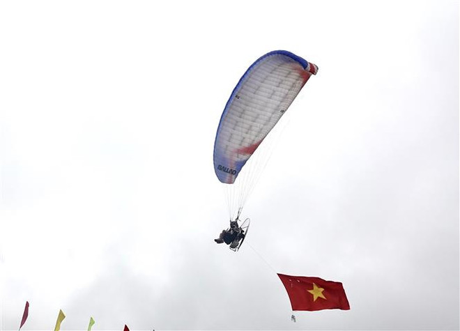 Du khách được chiêm ngưỡng màn bay biểu diễn dù bay của các phi công. (Ảnh: Tuấn Anh/TTXVN) Khai mạc Festival dù lượn “Bay trên mùa nước đổ” ảnh 1
