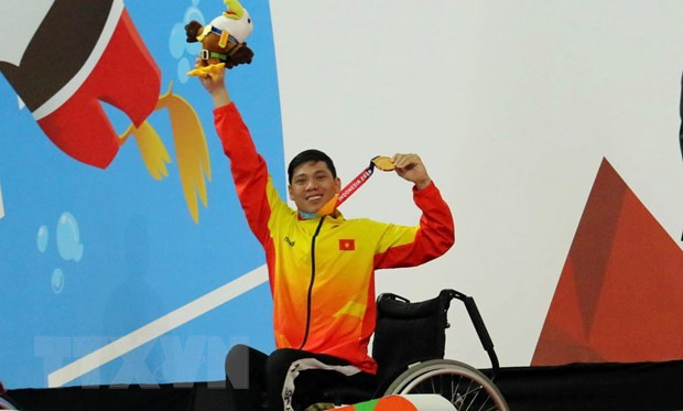 Vận động viên Võ Thanh Tùng tự hào giơ cao tấm huy chương vàng thứ 3 tại Asian Para Games 2018. (Ảnh: Hải Ngọc/TTXVN) Thể thao người khuyết tật song hành cùng dòng chảy thể thao nước nhà ảnh 1