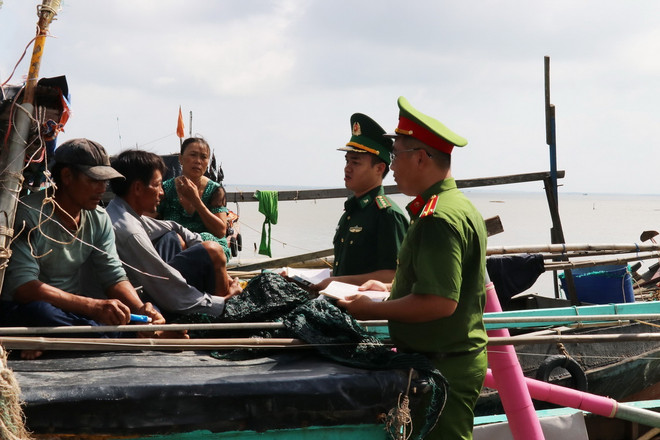 Cán bộ Đồn Biên phòng Tân Thành (Bộ đội Biên phòng Tiền Giang) phối hợp Công an xã Tân Thành tuyên truyền về phòng, chống khai thác IUU. (Ảnh: Hữu Chí/TTXVN) TTXVN_2706IUUTiengiang.jpg