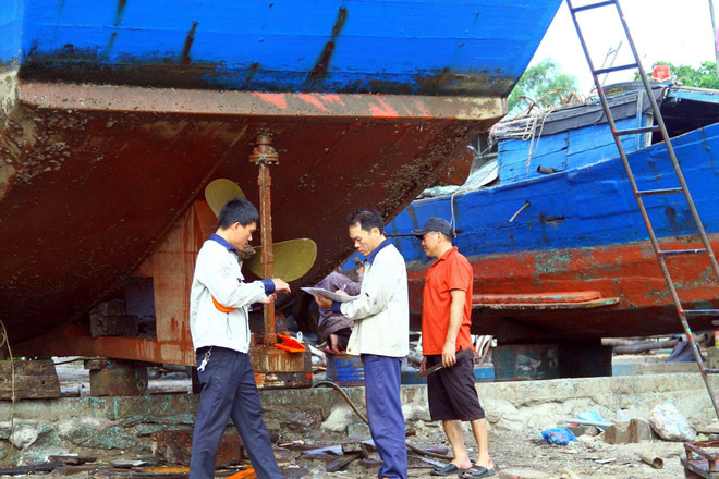 Cán bộ Trung tâm đăng kiểm (Chi cục Thủy sản Quảng Bình) kiểm tra tàu, thiết bị trên tàu để hoàn thành hồ sơ thủ tục cấp phép cho ngư dân. (Ảnh: Tá Chuyên/TTXVN) TTXVN_2506Quangbinh2.jpg
