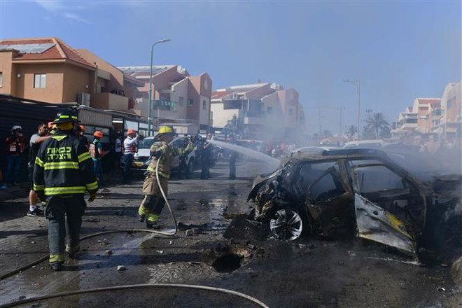 Lính cứu hỏa Israel dập lửa một phương tiện bị trúng rocket phóng từ Dải Gaza, tại thành phố Ashkelon ngày 16/5/2021. (Ảnh: THX/TTXVN) OIC họp khẩn kêu gọi quốc tế nỗ lực chấm dứt xung đột Israel-Palestine ảnh 2