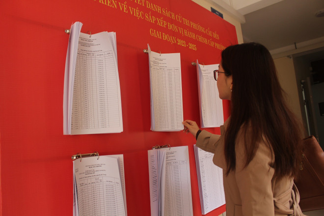 Người dân xem thông báo niêm yết danh sách cử tri, lấy ý kiến việc sắp xếp đơn vị hành chính cấp phường, trên địa bàn phường Cầu Dền. (Ảnh: Nguyễn Thắng/TTXVN) TTXVN_2902donvihanhchinh3.jpg