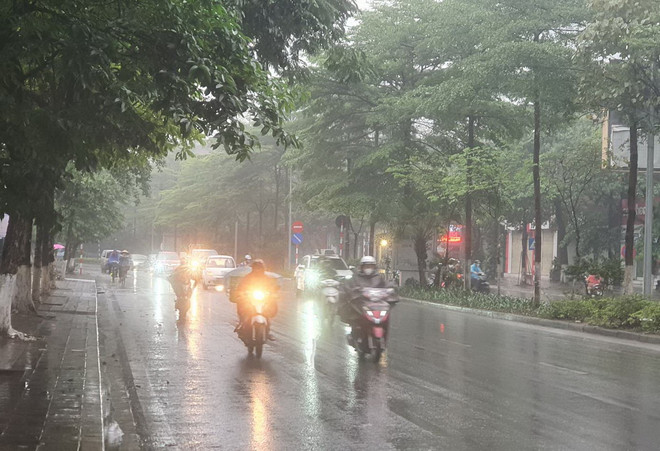 Người dân mặc áo mưa khi ra đường. (Ảnh: Huy Khánh/Vietnam+) Hà Nội tiếp tục nồm ẩm, nhiều nơi trên cả nước mưa lớn vào cuối tuần ảnh 1