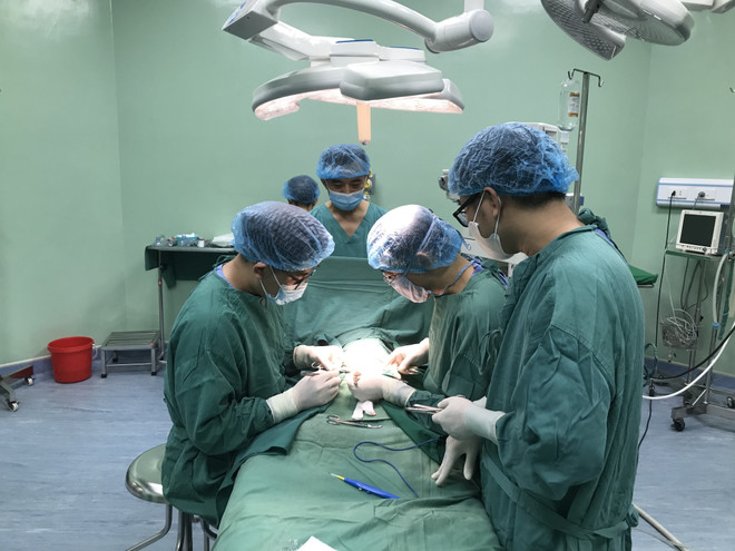 Bác sỹ Trần Minh Long (người đứng giữa, trên cùng) trong một ca phẫu thuật tại Bệnh viện Sản Nhi Nghệ An. (Ảnh: Bích Huệ/TTXVN) TTXVN_2702bacsyNgheAn2.jpg