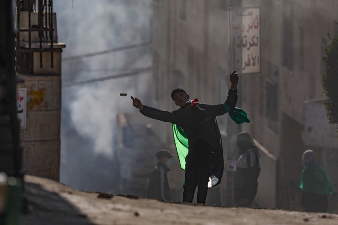 Người biểu tình Palestine ném đá về phía binh sỹ Israel trong cuộc xung đột tại thị trấn Al-Ram, Khu Bờ Tây ngày 27/1. (Ảnh: AFP/TTXVN) Nga kêu gọi Israel và Palestine tránh leo thang căng thẳng ảnh 1