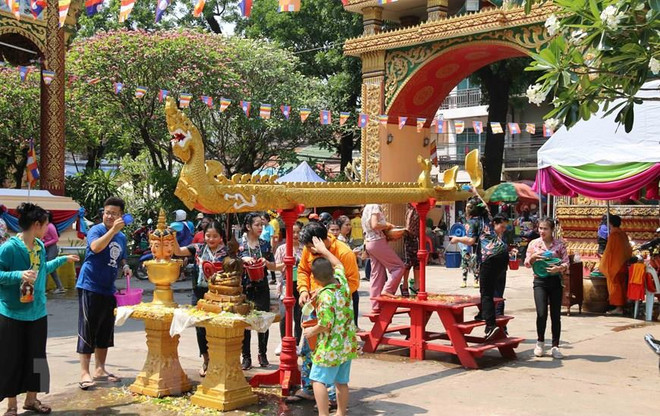 Trẻ nhỏ lấy nước tắm Phật xoa lên đầu người lớn để cầu chúc gặp nhiều may mắn. (Ảnh: Xuân Tú/TTXVN) Hội té nước - nét văn hóa đậm chất nhân văn của người Lào ảnh 1