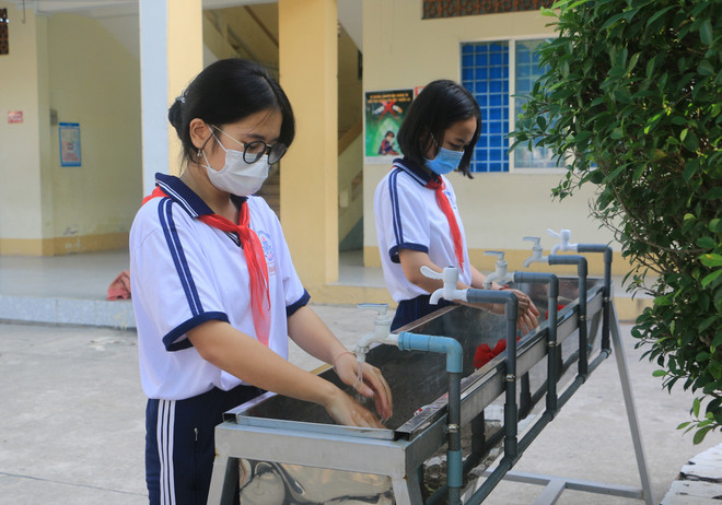 Học sinh Trường Trung học Cơ sở thị trấn Long Hồ, huyện Long Hồ rửa tay trước khi vào lớp. (Ảnh: Lê Thúy Hằng/TTXVN) Học sinh Thanh Hóa, Vĩnh Long, Cần Thơ đến trường sau nghỉ phòng dịch ảnh 2