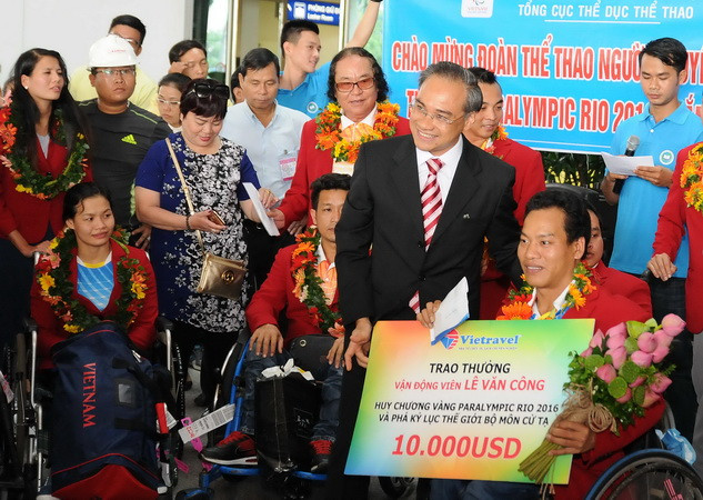 Đại diện các đơn vị, doanh nghiệp trao phần thưởng cho vận động viên Lê Văn Công-HCV Paralympic Rio 2016 và phá kỷ lục thế giới môn cử tạ. (Ảnh: An Hiếu/TTXVN) Chào đón đoàn thể thao người khuyết tật Việt Nam đại thắng trở về ảnh 1
