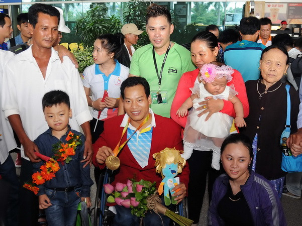 Vận động viên Lê Văn Công - HCV Paralympic Rio 2016 và phá kỷ lục thế giới môn cử tạ bên cạnh gia đình và người hâm mộ. (Ảnh: An Hiếu/TTXVN) Chào đón đoàn thể thao người khuyết tật Việt Nam đại thắng trở về ảnh 2