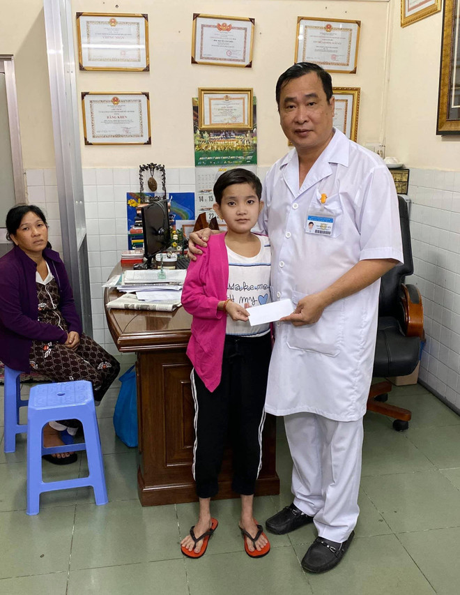Bác sỹ Nguyễn Văn Tiến trao tiền hỗ trợ cho "cô bé ễnh ương" Lê Thị Diễm sau phẫu thuật. (Ảnh: Đinh Hằng/TTXVN) Bác sỹ Nguyễn Văn Tiến: "Ông Bụt áo trắng" của các bệnh nhân nghèo ảnh 2