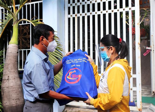 Đại diện Hội đồng nhân dân Tp. Hồ Chí Minh trao quà tặng và động viên công nhân ở trọ, người lao động có hoàn cảnh khó khăn ở Quận 8. (Ảnh: Thanh Vũ/TTXVN) TP.HCM, Hà Nội tiếp tục hỗ trợ người lao động có hoàn cảnh khó khăn ảnh 1