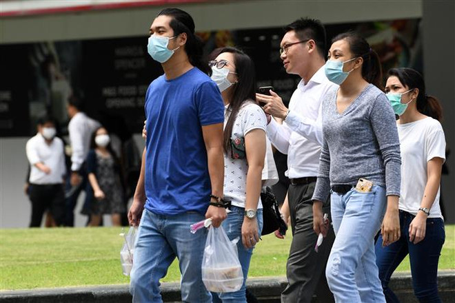 Người dân Singapore đeo khẩu trang phòng dịch viêm đường hô hấp cấp do virus COVID-19 tại quận Raffles, Singapore ngày 5/2/2020. (Ảnh: AFP/TTXVN) Singapore áp dụng biện pháp cách ly tại nhà nghiêm ngặt hơn ảnh 1