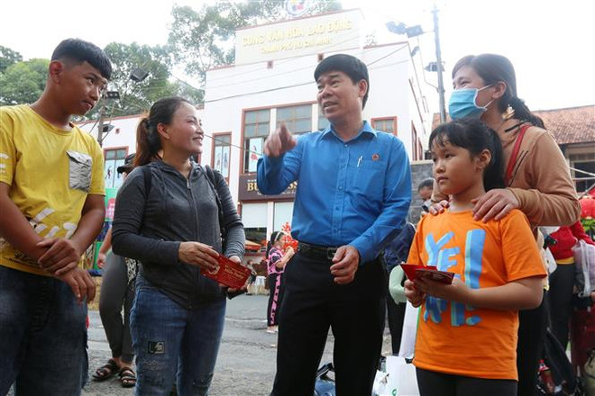 Ông Phạm Chí Tâm, Phó Chủ tịch Liên đoàn Lao động Thành phố Hồ Chí Minh thăm hỏi, động viên các công nhân về quê đón Tết. (Ảnh: Thanh Vũ/TTXVN) Những chuyến xe Xuân nghĩa tình: 20 năm chuyên chở niềm vui ảnh 3