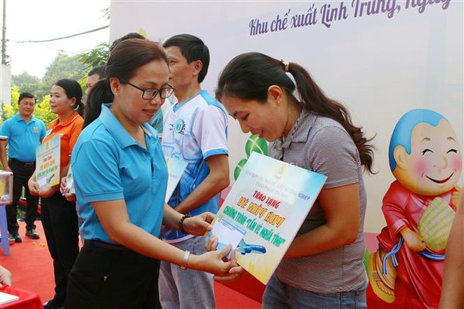 Đại diện Ban Quản lý Hepza Thành phố Hồ Chí Minh trao tấm vé nghĩa tình cho công nhân lao động Khu chế xuất Linh Trung. (Ảnh: Thanh Vũ/TTXVN) Những chuyến xe Xuân nghĩa tình: 20 năm chuyên chở niềm vui ảnh 2