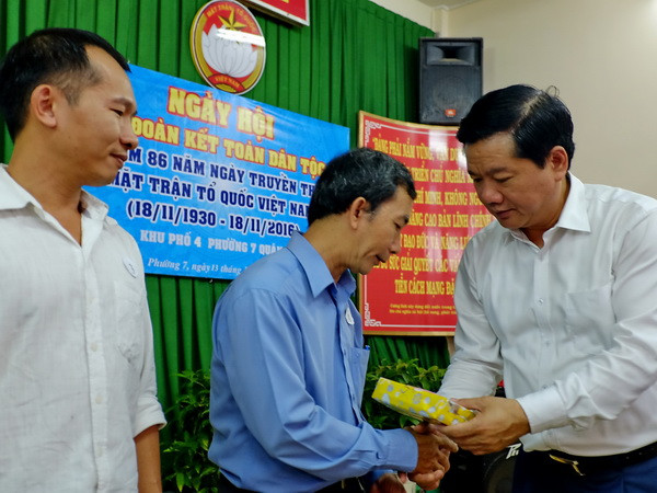 Ủy viên Bộ Chính trị, Bí thư Thành ủy Thành phố Hồ Chí Minh Đinh La Thăng tặng quà cho các gia đình chính sách khó khăn tại Khu phố 4, phường 7, quận 3. (Ảnh: Thế Anh/TTXVN) Chung tay xây dựng Thành phố Hồ Chí Minh có chất lượng sống tốt ảnh 1