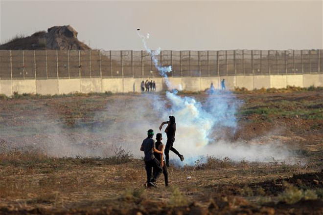 Người biểu tình Palestine ném trả đạn hơi cay về phía binh sĩ Israel trong cuộc đụng độ tại khu vực biên giới Dải Gaza-Israel, ngày 1/9/2023. (Ảnh: THX/TTXVN) Mỹ tài trợ vũ khí cho Palestine ổn định an ninh ở Bờ Tây ảnh 1