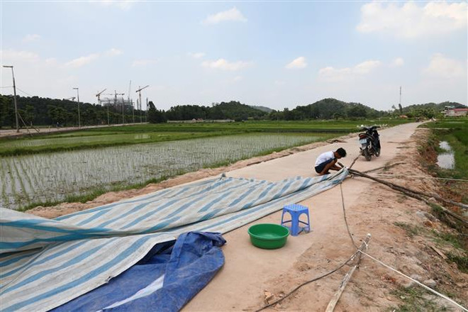 Người dân xã Nam Sơn bắt đầu tháo dỡ lều bạt đã căng, chặn mấy ngày qua. (Ảnh: Thành Đạt/TTXVN) Người dân sống gần bãi rác Nam Sơn tháo dỡ lều bạt, ngừng chặn xe ảnh 1