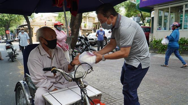 Nhiều suất cơm, phần quà vẫn tiếp tục được chia sẻ với người nghèo tại TP.HCM dù đã kết thúc thời gian giãn cách xã hội. (Ảnh: Thanh Vũ/TTXVN) Sức mạnh của tinh thần đại đoàn kết trong cuộc chiến với COVID-19 ảnh 1