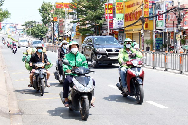 Lực lượng giao hàng công nghệ (shipper) được hoạt động trở lại tại 8 địa phương vùng đỏ ở TP.HCM. (Ảnh: Tiến Lực/TTXVN) Những con người lặng lẽ trong tâm dịch: Nối mạch an sinh xã hội ảnh 2