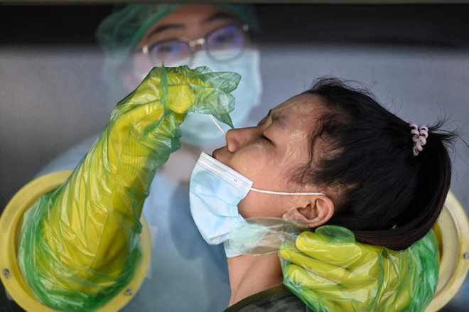 Nhân viên y tế lấy mẫu xét nghiệm COVID-19 cho người dân tại Bangkok, Thái Lan. (Ảnh: AFP/TTXVN) 'Sống chung' với COVID-19 - Mô hình mới của nhiều quốc gia thế giới ảnh 3