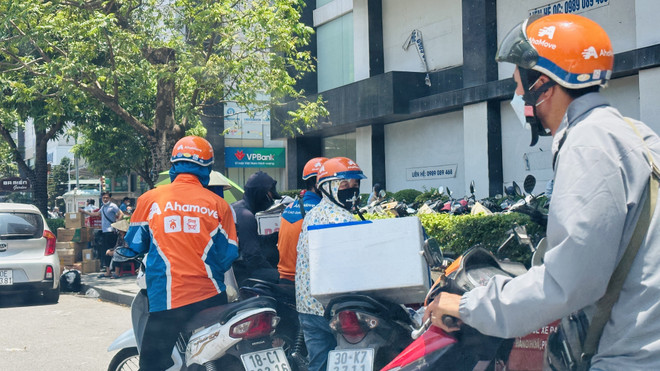 Shipper công nghệ đứng trên phố Vũ Trọng Phụng (quận Thanh Xuân, Hà Nội) chờ giao hàng cho khách giữa cái nắng nóng oi bức đầu hè. (Ảnh: Minh Nghĩa/TTXVN) Hà Nội: Người lao động vất vả mưu sinh giữa trời nắng nóng ảnh 2