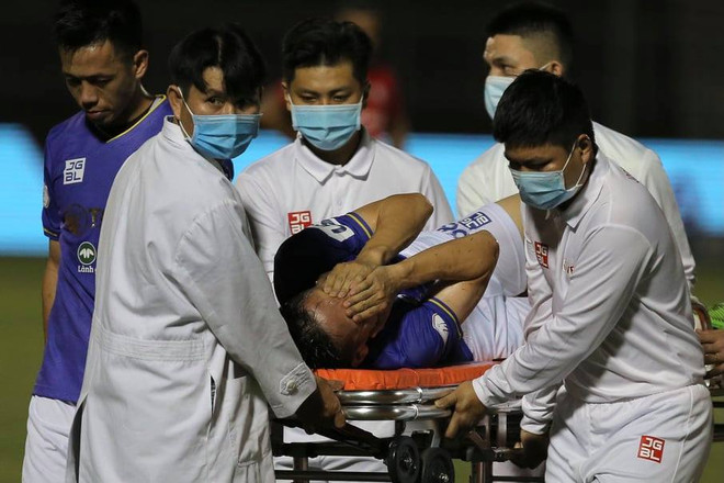 Hùng Dũng đau đớn khi được đưa ra xe cứu thương bằng cáng. (Ảnh: Hải An/Vietnam+) Thắng đậm TP.HCM, Hà Nội FC tạm leo lên ngôi đầu V-League 2021 ảnh 2