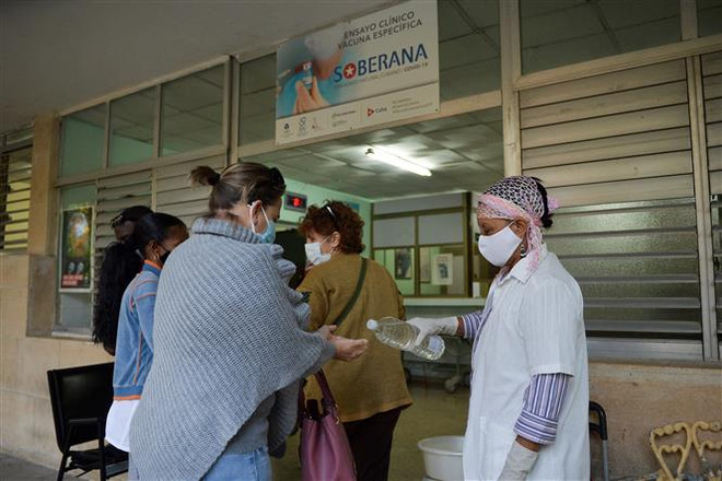 Sát khuẩn tay trước khi vào một điểm tiêm chủng vaccine ngừa COVID-19 ở Havana,Cuba. (Ảnh: AFP/TTXVN) Dịch COVID-19 lắng dịu ở Nhật Bản, Cuba nhưng tăng mạnh tại Singapore ảnh 2