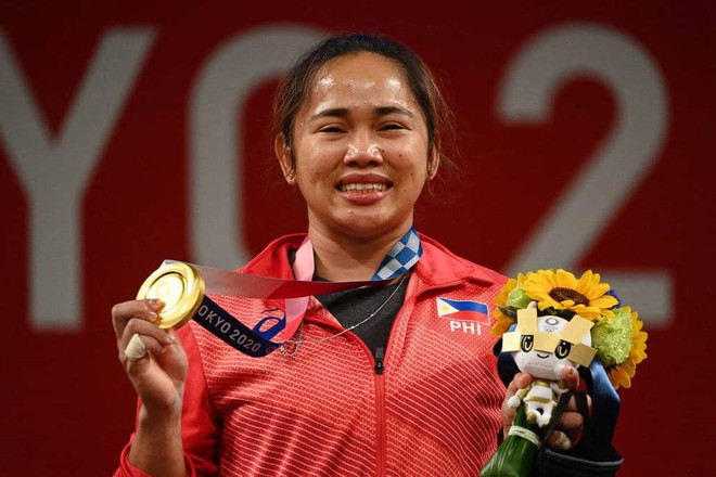 Hidilyn Diaz trên bục nhận tấm huy chương Vàng lịch sử. (Nguồn: AFP) Nữ đô cử Philippines nhận thưởng hậu hĩnh sau tấm HCV lịch sử ảnh 1