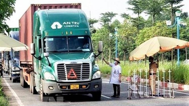 Lực lượng chức năng hướng dẫn tạo “luồng xanh” cho các phương tiện vận tải. (Ảnh: TTXVN) Nghị quyết 105 - chỗ dựa cho doanh nghiệp trong đại dịch COVID-19 ảnh 3