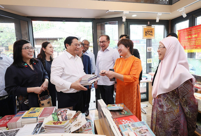Thủ tướng Phạm Minh Chính mua sách tặng Thủ tướng Malaysia Anwar Ibrahim và Phu nhân. (Ảnh: Dương Giang/TTXVN) Thủ tướng Việt Nam và Malaysia cùng thăm phố sách, thưởng thức càphê ảnh 1