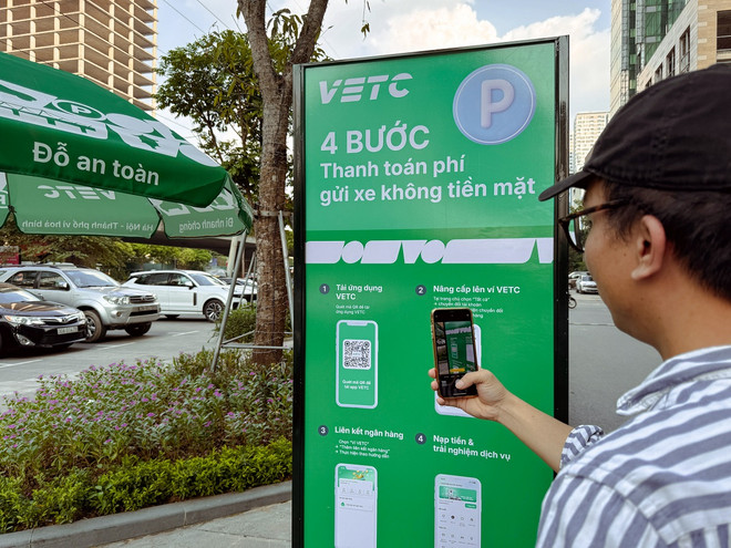 Người dân tham khảo hướng dẫn thanh toán nhanh gọn qua ví VETC. (Ảnh: PV/Vietnam+) Thu phí đỗ xe qua VETC - 2.jpg