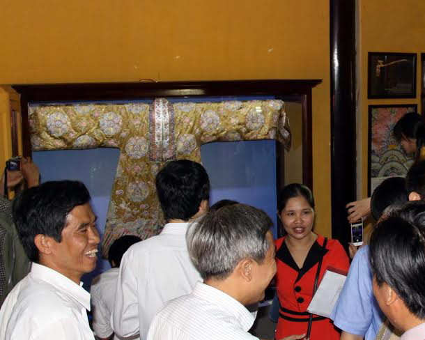 Khách tham quan trang phục đại triều của Hoàng Thái hậu. (Ảnh: Quốc Việt/Vietnam+) Hoa văn trên trang phục của phụ nữ cung đình triều Nguyễn ảnh 1