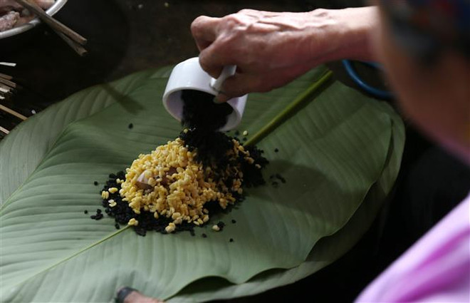 Đồng bào dân tộc người Dáy (Lào Cai) gói bánh chưng đen chuẩn bị đón Tết. (Ảnh: Quốc Khánh/TTXVN) Bí ẩn sau chiếc bánh chưng đen và bánh dầy ngũ sắc tại Lào Cai ảnh 1