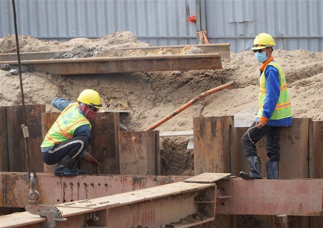 Công nhân thi công tại dự án hầm chui nút giao thông Nguyễn Văn Linh - Nguyễn Hữu Thọ giữa tháng 7/2021. (Ảnh: Tiến Lực/TTXVN) Những chính sách kinh tế mới có hiệu lực từ tháng 2 ảnh 2