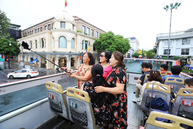 Du khách hào hứng khi được tham quan Hà Nội bằng xe buýt 2 tầng. (Ảnh: Tuấn Anh/TTXVN) ttxvn_du_lich_ha_noi_1504-2.jpg