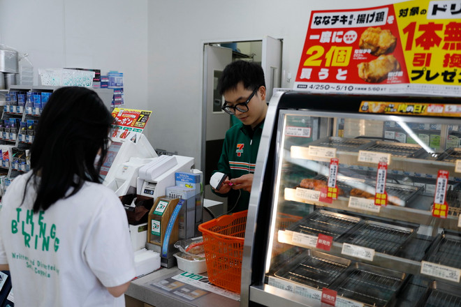 Anh Minh Đức tính tiền cho khách hàng tại cửa hàng tiện lợi 24/24 Seven-Eleven. (Ảnh: Xuân Giao/TTXVN) ttxvn_nguoi viet tai nhat (1).jpg