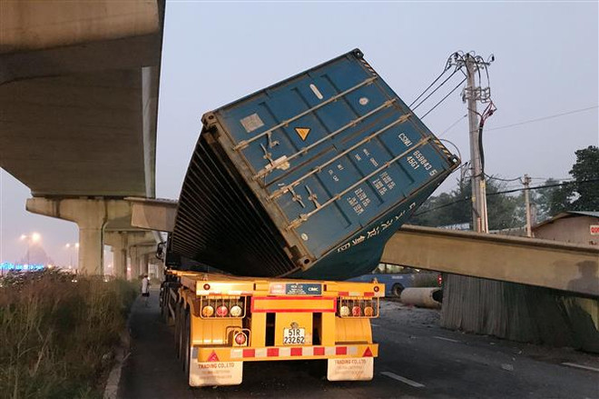 Xe container bị dầm bêtông đè lên nóc. (Ảnh: TTXVN phát) Đang xác định nguyên nhân vụ xe container kéo sập dầm cầu bộ hành ảnh 1