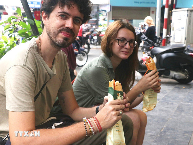 ភ្ញៀវទេសចរបរទេសចូលរួមកម្សាន្តនៅតាមដងផ្លូវនៃទីក្រុងហាណូយ។ (រូបថត៖ VNA) ttxvn-am-thuc-duong-pho-ha-noi-hap-dan-khach-du-lich-2-6405.jpg