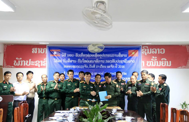 Đại diện Bộ Tư lệnh Thông tin liên lạc, Bộ Quốc phòng Việt Nam (trái) và Đại tá Sayaphon Chanthavong (phải), Cục trưởng Cục trưởng Cục Thông tin, Bộ Tổng tham mưu Quân đội Nhân dân Lào, đang trao cho nhau Biên bản bàn giao trang thiết bị tại buổi lễ. (Ảnh: Phạm Kiên/Vietnam+) Việt Nam hỗ trợ trang thiết bị, khí tài thông tin cho Quân đội Lào ảnh 1