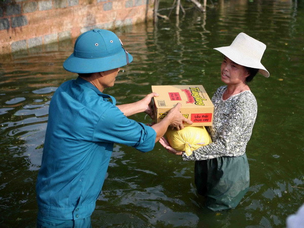 Quà hỗ trợ của Hội Chữ thập Đỏ thành phố Hà Nội được giao tận tay người dân trong vùng ngập. (Ảnh: Thanh Tùng/TTXVN) Đảm bảo không để người dân bị đói, rét do ảnh hưởng bão, lũ ảnh 1