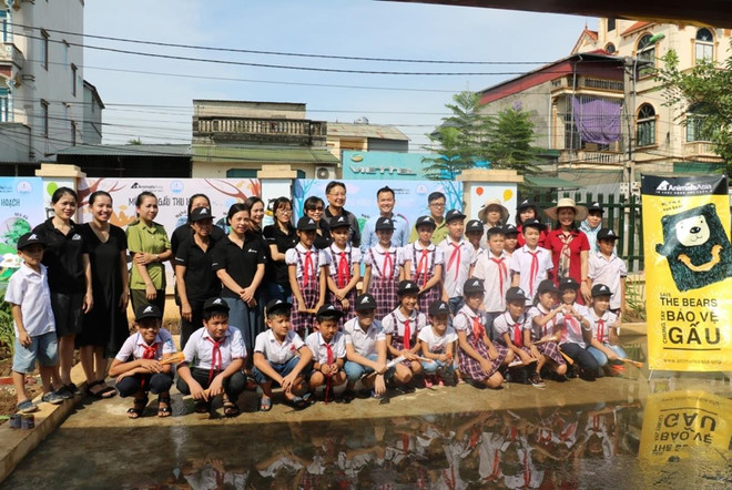 Các vị khách và thầy cô cùng chụp ảnh với các em học sinh sau khi hoàn thành vườn cây. (Ảnh: TCĐVCA cung cấp) Hà Nội: Khởi động trồng vườn thảo dược bảo vệ gấu tại trường tiểu học ảnh 2